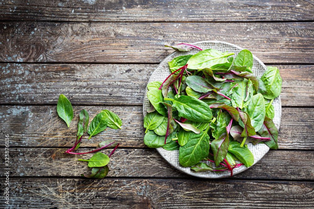 Healthy salad, leaves mix salad with mangold and spinach in the plate over wooden background, top view. Food background. Healthy salad, leaves mix salad with mangold and spinach in the plate over wooden background, top view. Food background.