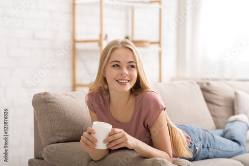Cheerful blonde girl drinking tea at home