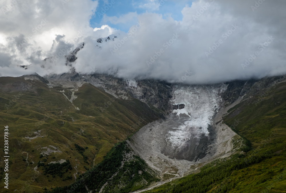 Dramatic autumn landscape with glacier Lardaad Adishi and mountain Tetnuldi hiding in clouds in Svaneti Georgia big kar and small tongue because of global warming Dramatic autumn landscape with glacier Lardaad Adishi and mountain Tetnuldi hiding in clouds in Svaneti Georgia big kar and small tongue because of global warming