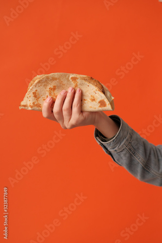 Mexican national food taco or Tatar national food kystyby in hand on an orange background.Food in a tortilla.National food concept photo