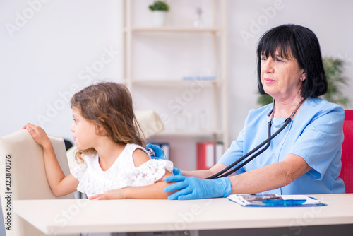 Little girl visiting old female doctor