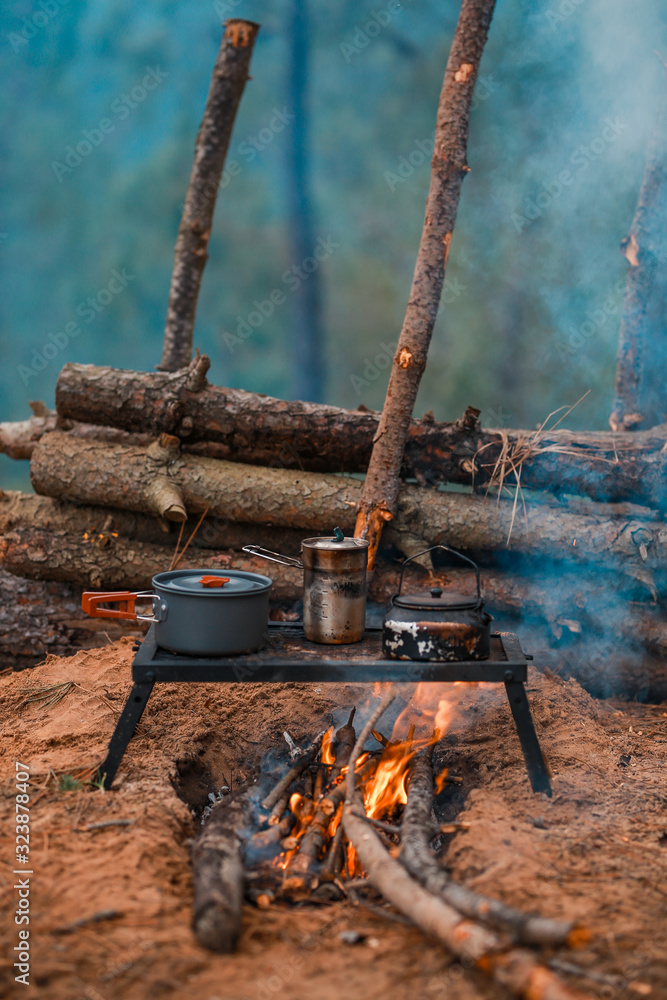 Primitive Bushcraft survival debris hut with campfire ring outside.  Blanket, shelter, fire in the forest. Stock Photo