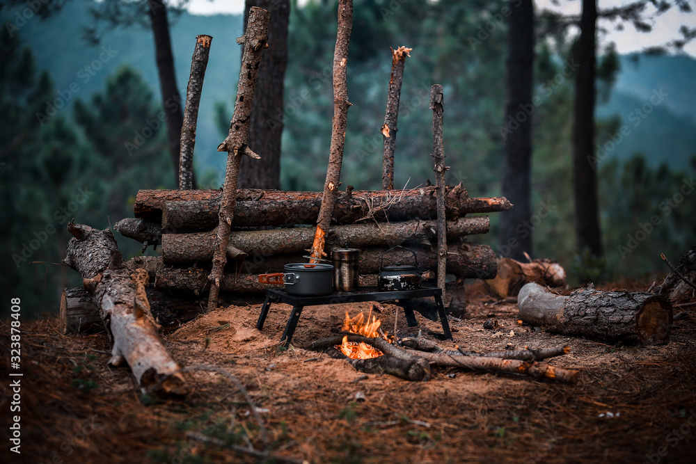 Primitive Bushcraft survival debris hut with campfire ring outside