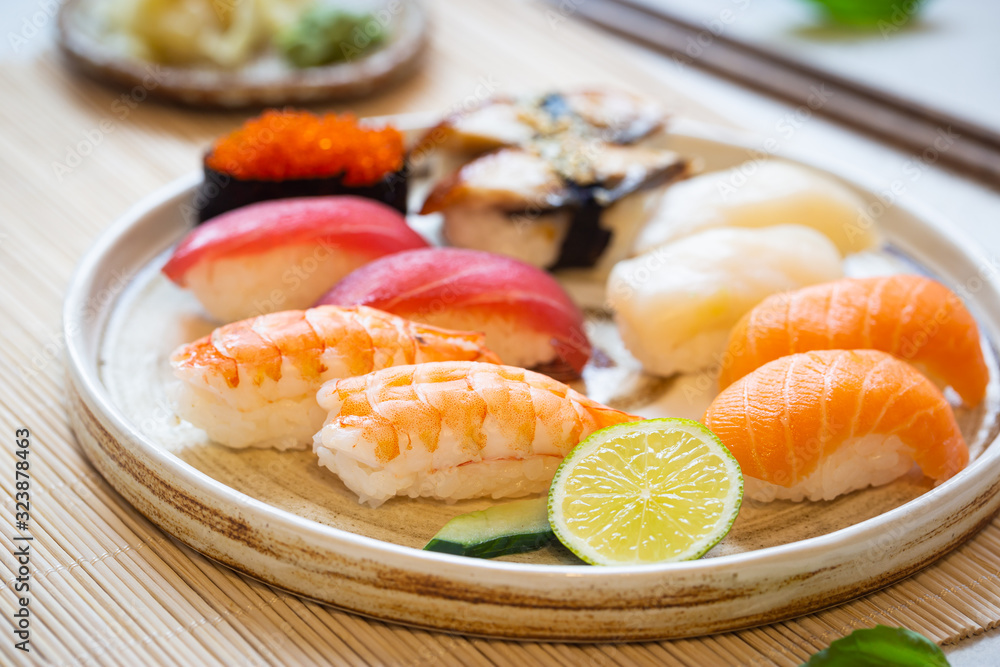 Set of sushi and maki on plate with soy sauce and chopsticks on white background. Top view with copy space