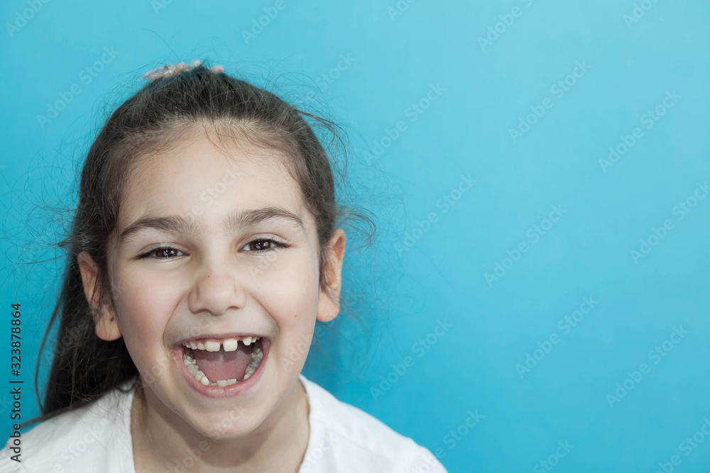 Portrait of happy laughing child girl on blue background. Smiling kid. Positive emotions. Portrait of happy laughing child girl on blue background. Smiling kid. Positive emotions.