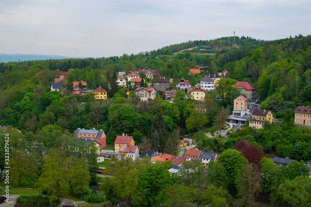 Typical colorful czech houses in Loket, a picturesque town in Czech Republic, with the green trees of the mountain at the background