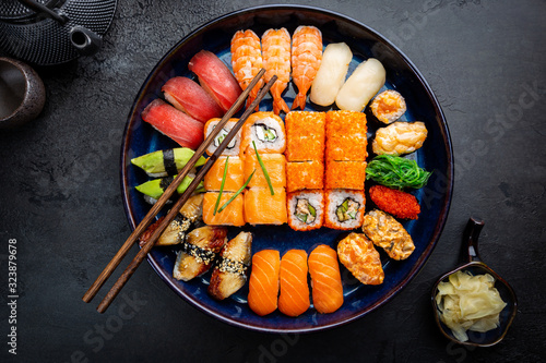 Foto Set of sushi and maki with soy sauce over black background