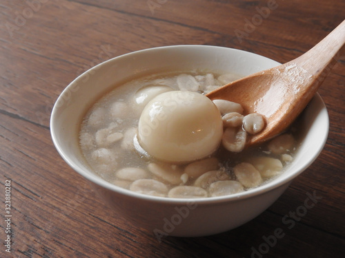 High angle view of a bowl of peanut soup isolated on wooden background. Wooden spoon scooping up dumpling.Peanut also called groundnut. High oil content. Taiwan food, dessert and agriculture concept.