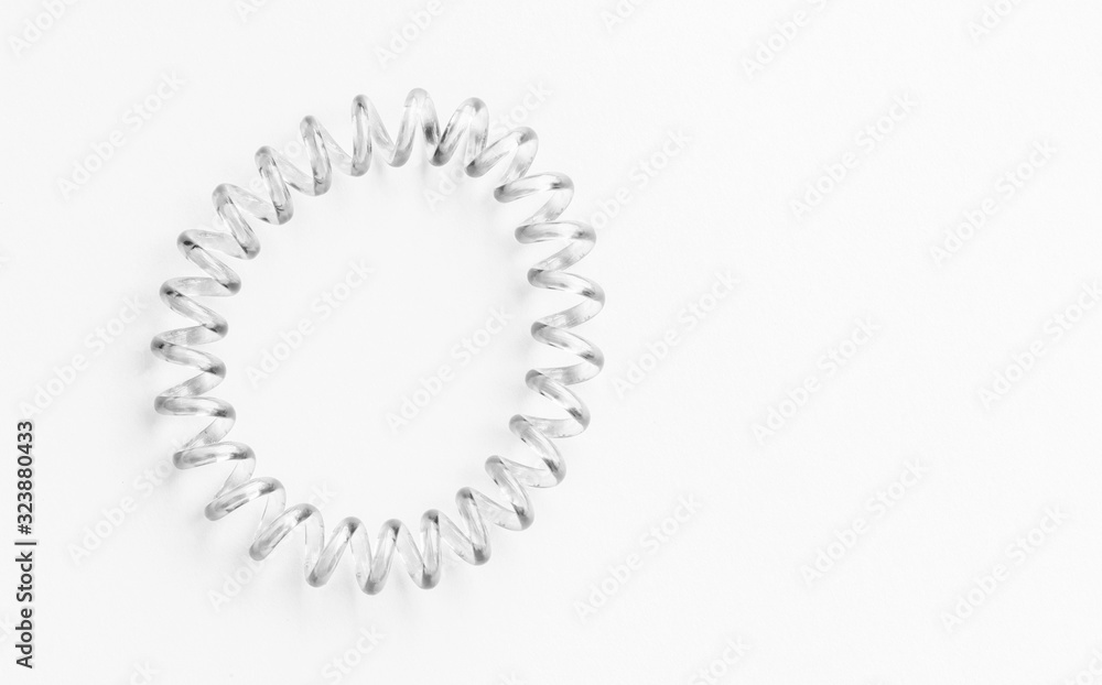 Transparent elastic spiral hair band for women or girls isolated on white background. With clipping path. Modern plastic transparent rubber, tie for girlish long hair hairstyles. copy space Transparent elastic spiral hair band for women or girls isolated on white background. With clipping path. Modern plastic transparent rubber, tie for girlish long hair hairstyles. copy space