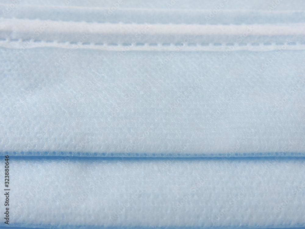 Naklejka premium Close up of a blue disposable surgical mask. Novel coronavirus (COVID-19). Health and medical concept. Face mask background. Non-woven fabric.
