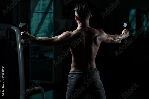Bodybuilder Exercising Shoulders With Dumbbells