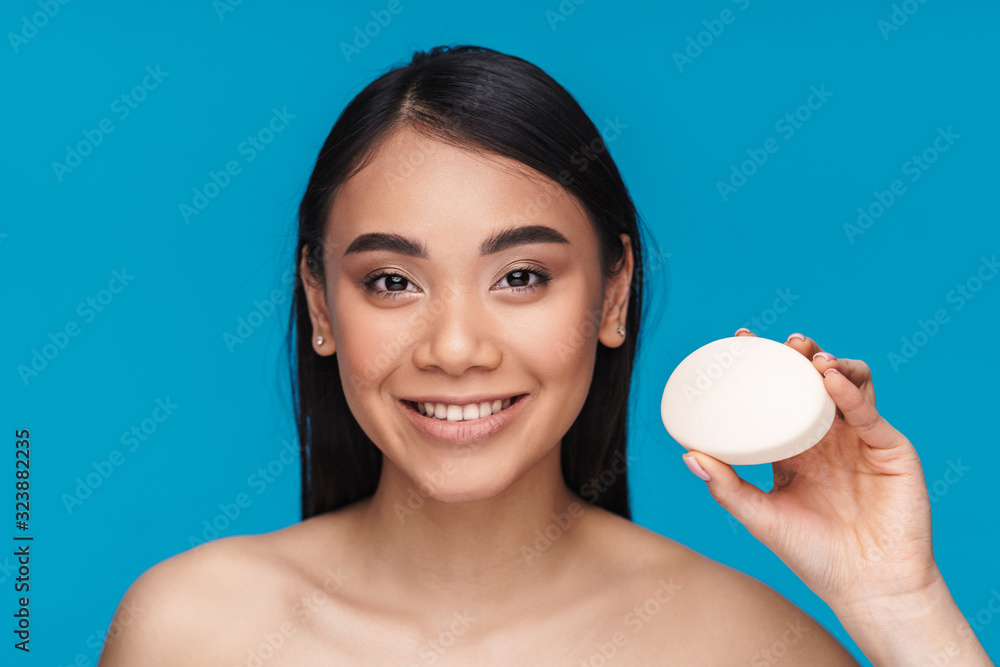 Woman posing isolated over blue wall holding soap. Woman posing isolated over blue wall holding soap.