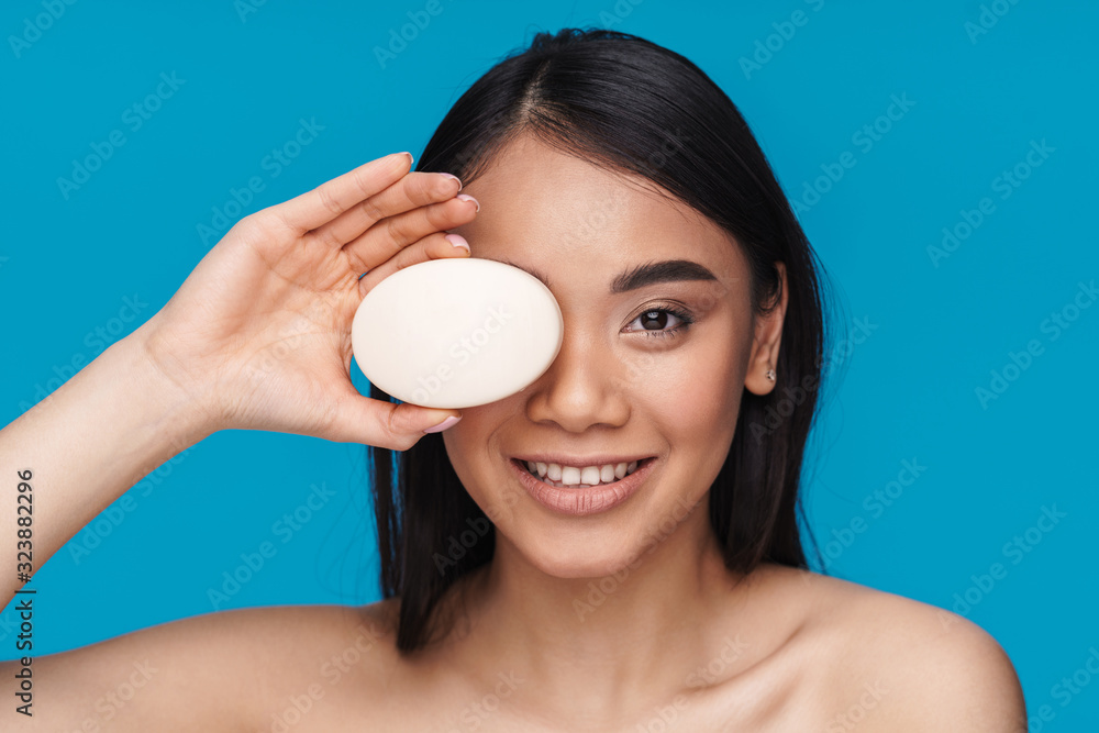 Woman posing isolated over blue wall holding soap. Woman posing isolated over blue wall holding soap.