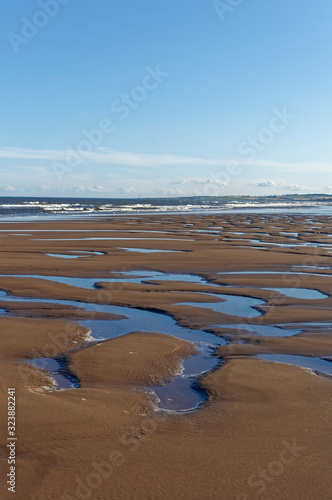 Obraz na płótnie Pools of water in the sand left behind by the retreating tide at St Cyrus Nature Reserve beach on a Summers Evening