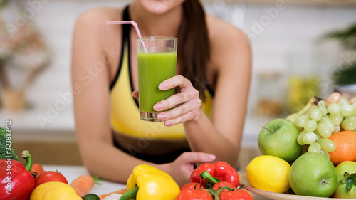Fit woman holding glass of vegetable detox smoothie