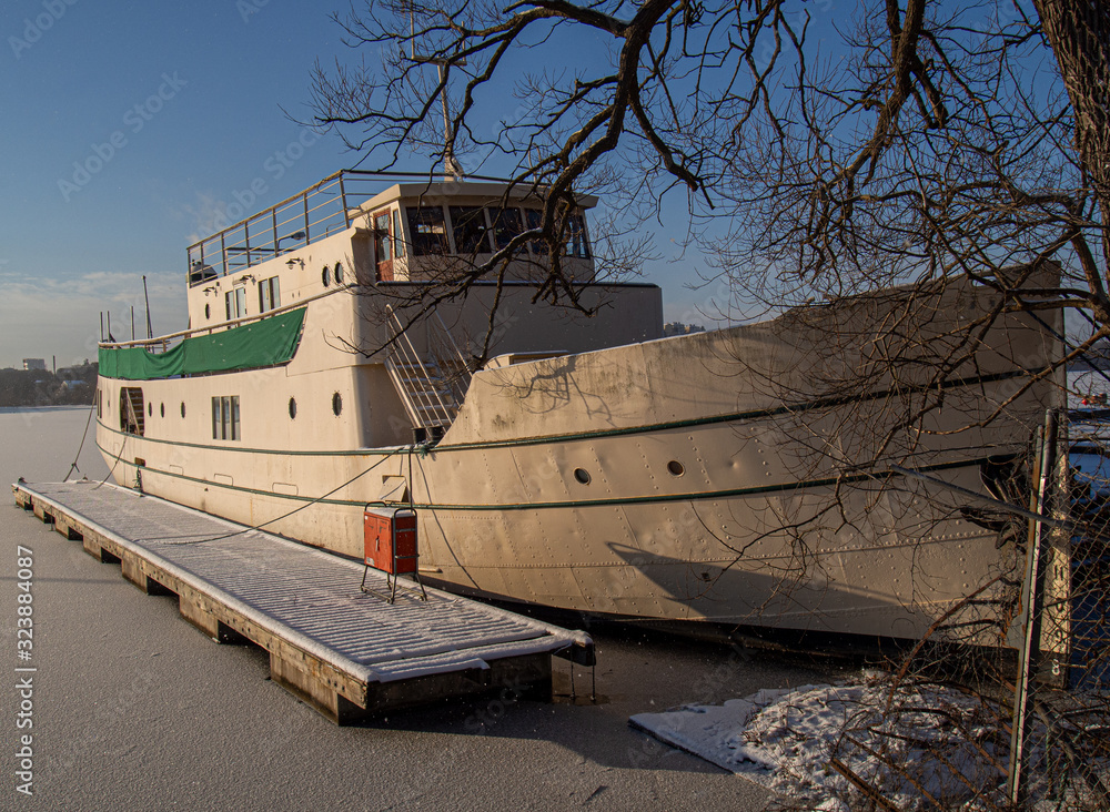 Fototapeta premium large steel boat moored by small pier and frozen lake