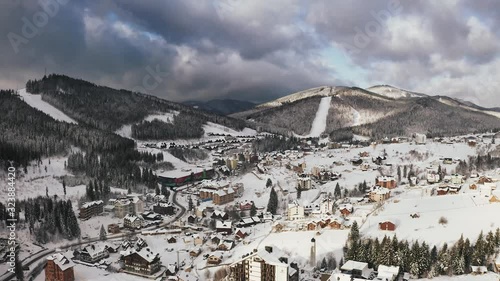 Aerial footage of ski resort village in winter time during sunny day with epic clouds photo