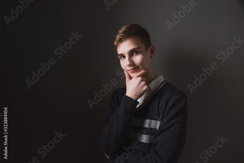 Lifestyle photo of a young brown-haired man on a light background, a beautiful young guy in a shirt and sweater