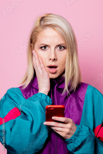Surprised mlonde woman in sport siut of 90s on pink background