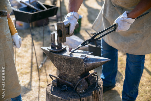 Rustic blacksmith forges hot metal product on the anvil. Production metal products manually. Details handmade of metal