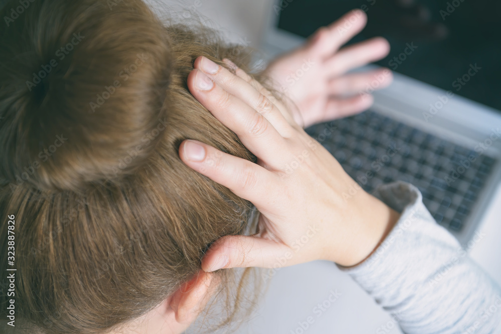 Fototapeta premium Stressed businesswoman touching head with hands and looking at the laptop screen