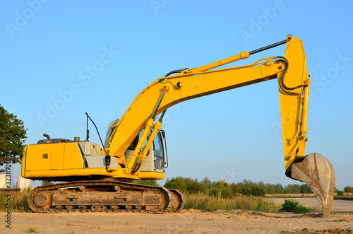 Bucked tracked excavator digs ground at a construction site for installing concrete storm pipes. Backhoe the digging pipeline ditch. Commercial and Public Civil Work Contracting  trenching  tamps soil