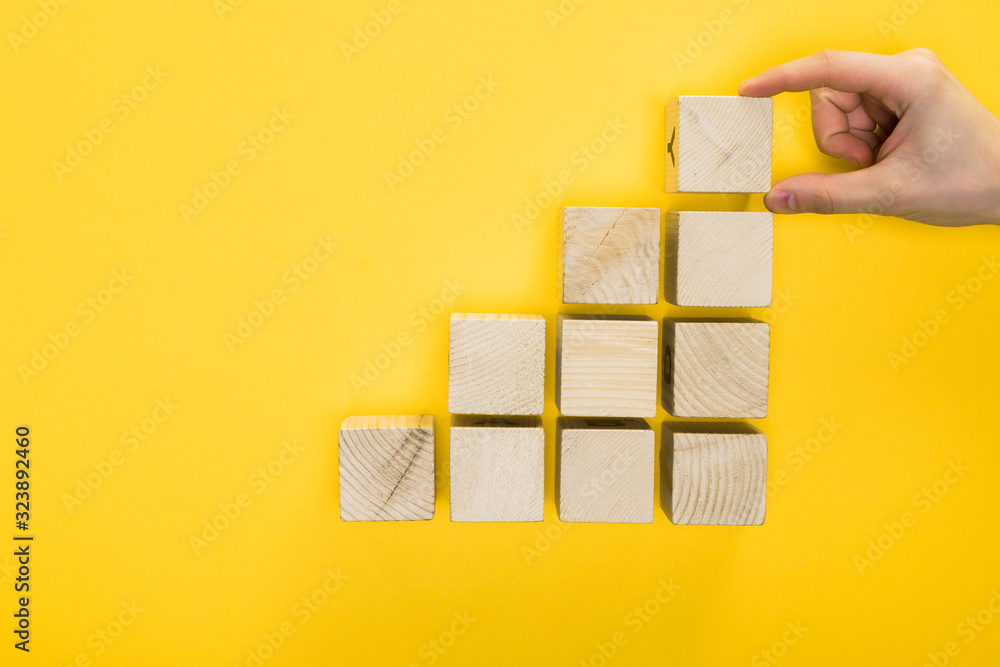 top view of man holding wooden cube isolated on yellow top view of man holding wooden cube isolated on yellow