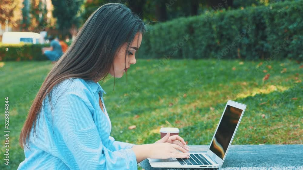 Attractive brunette girl student is using laptop in city center, being inspired by nature beauty. Close up. Copy space. 4K. Attractive brunette girl student is using laptop in city center, being inspired by nature beauty. Close up. Copy space. 4K.