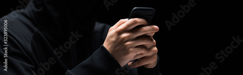 panoramic shot of hacker using smartphone isolated on black