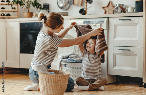 Happy family mother housewife and child   in laundry with washing machine . photo