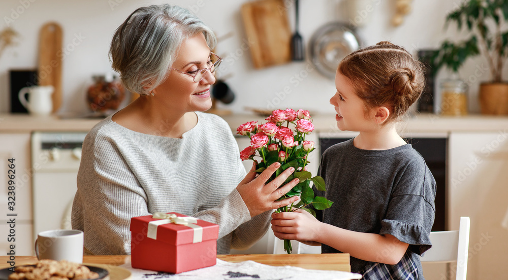 happy family. child granddaughter congratulates her grandmother and gives her flowers and a gift. happy family. child granddaughter congratulates her grandmother and gives her flowers and a gift.