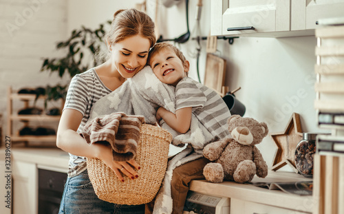 Happy family mother housewife and child   in laundry with washing machine . photo