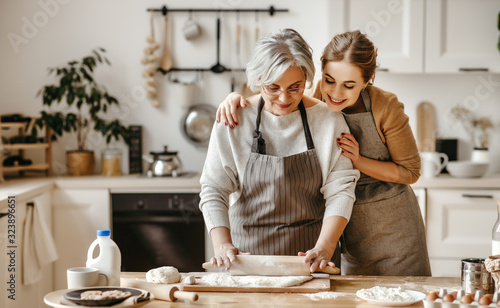 happy family grandmother  old mother mother-in-law and daughter-in-law daughter cook in kitchen, knead dough, bake cookies.