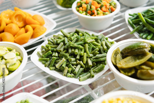 String beans lies on a white plate. Frozen vegetables, next to the plates are a variety of frozen vegetables and fruits.