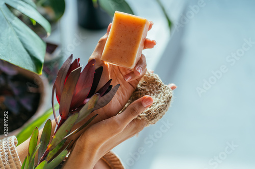 Woman hands holding natural organic solid green soap bar made with olive oil on blue background. Healthy lifestyle, beauty, skin care. Zero waste home concept. © Iryna