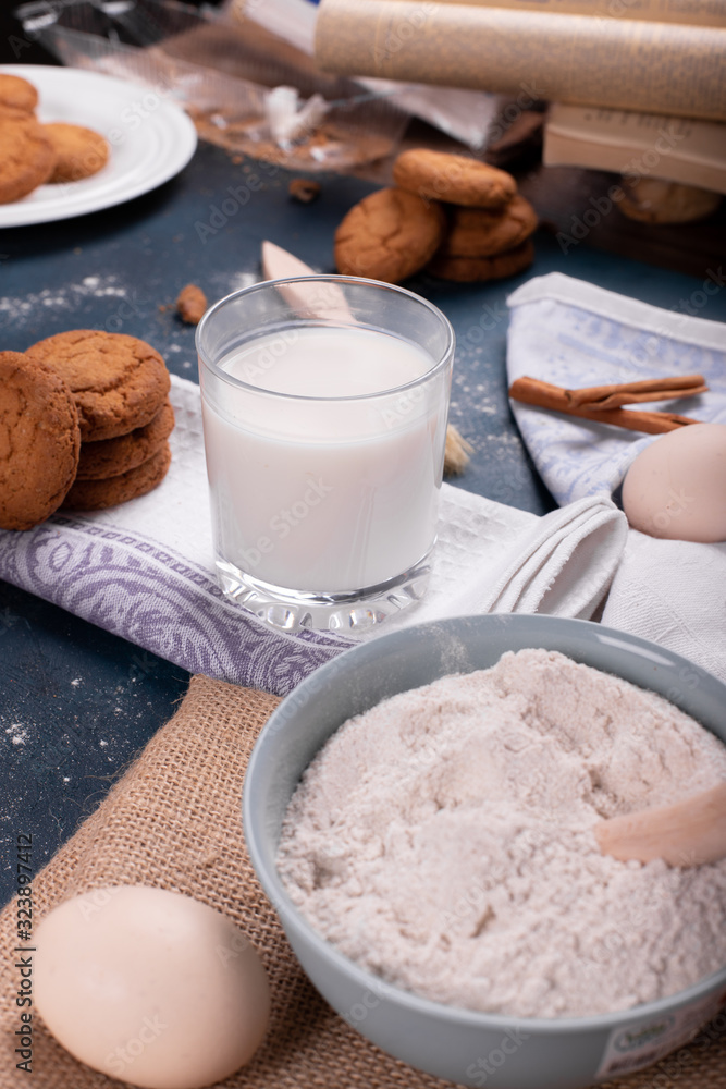 Cup of milk with jar of biscuits and flour