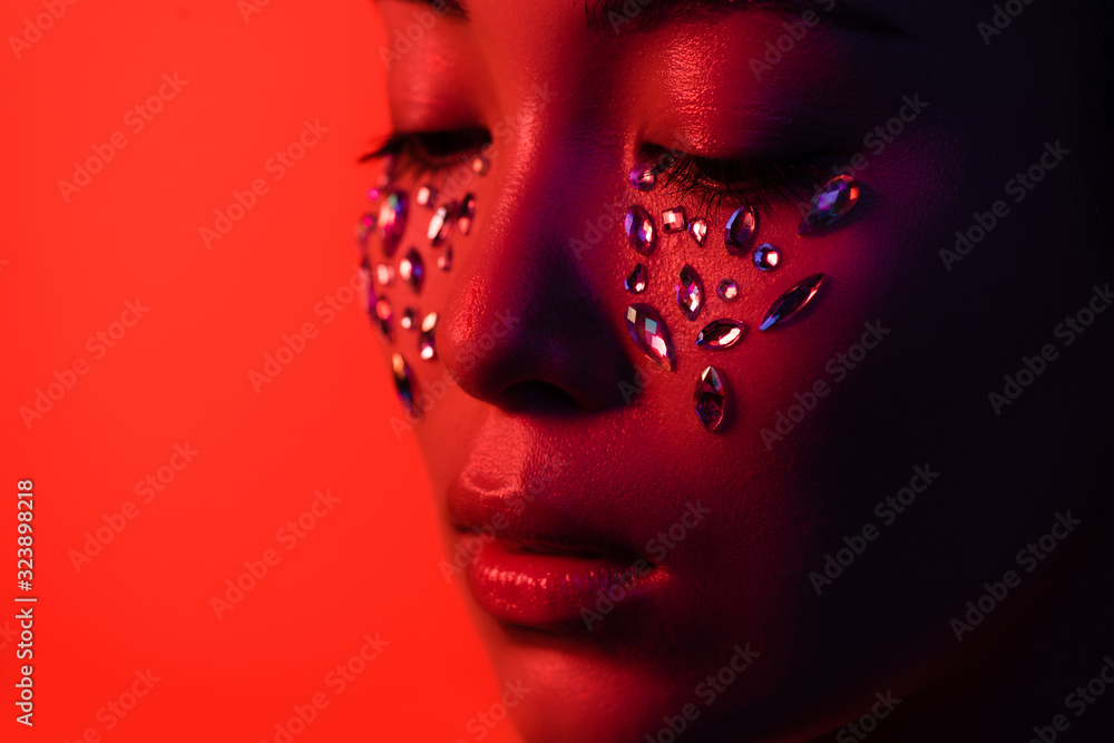 beautiful asian girl with rhinestones on face isolated on red