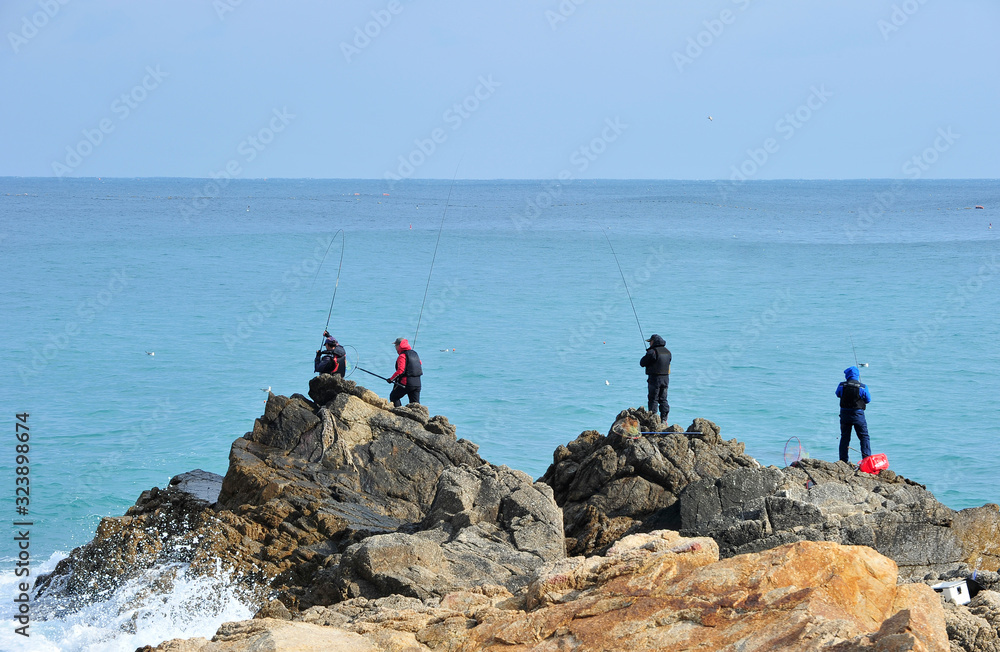 Korean fishermen fishing from the rocks on the seashore
