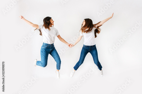 Two girls in casual clothes jump high