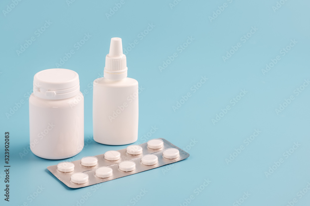 two white plastic medicine bottles for pills without labels and pill packaging on blue background. Copy space for text two white plastic medicine bottles for pills without labels and pill packaging on blue background. Copy space for text