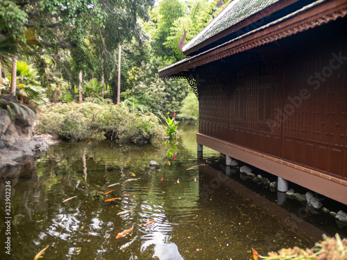 Beautiful image of traditional thailand wooden house on stilts near pond with red koi carp fishes