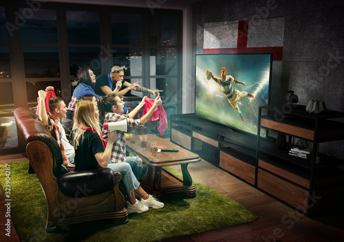 Group of friends watching TV, match, championship, sport games. Emotional men and women cheering for favourite rugby team of England with flag. Concept of friendship, sport, competition, emotions.