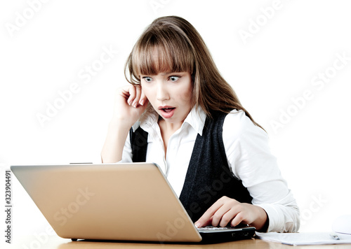 Shocked young girl is looking at a laptop reading messages in social networks. The concept of discounts in online stores. Online shopping concept. Copyspace