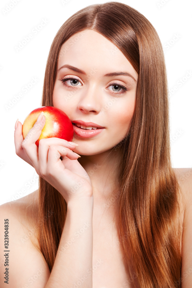 Beautiful girl with long brown hair holding apple in her right hand in front of face, looking at camera, isolated on white background Beautiful girl with long brown hair holding apple in her right hand in front of face, looking at camera, isolated on white background