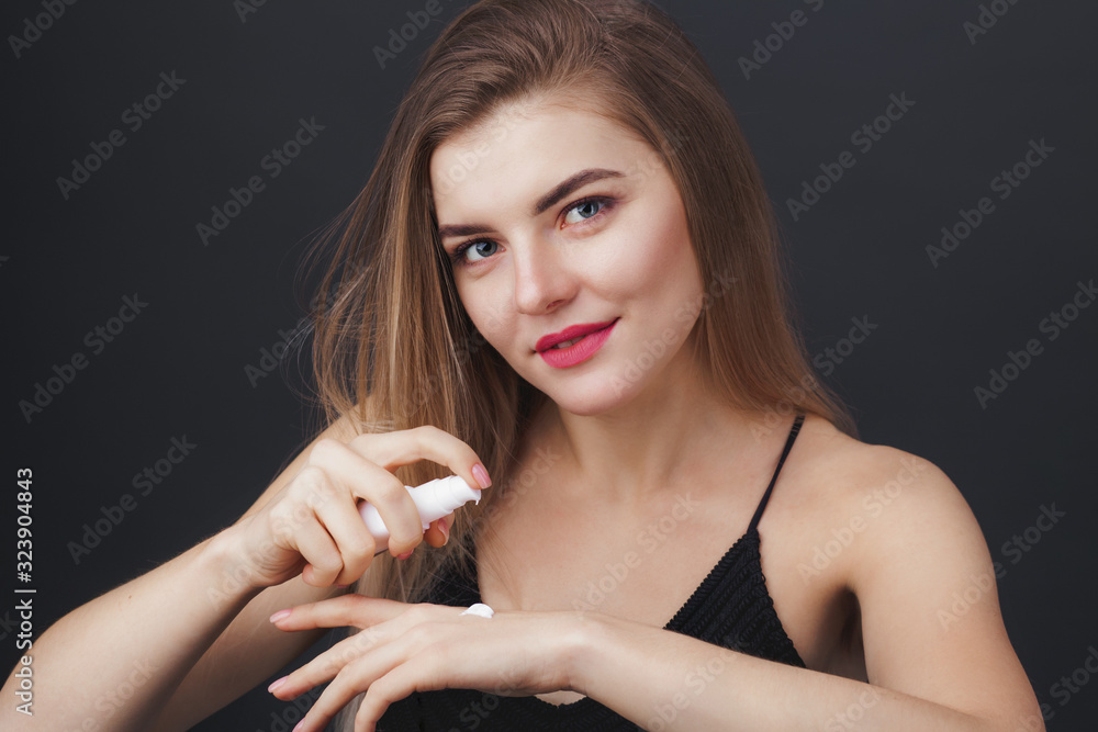 Obraz premium Lovely woman with perfect healthy look applying skin care product