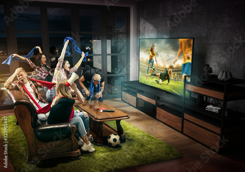 Group of friends watching TV, match, championship, sport games. Emotional men and women cheering for favourite female soccer team, emotions. Concept of friendship, sport, competition, emotions.