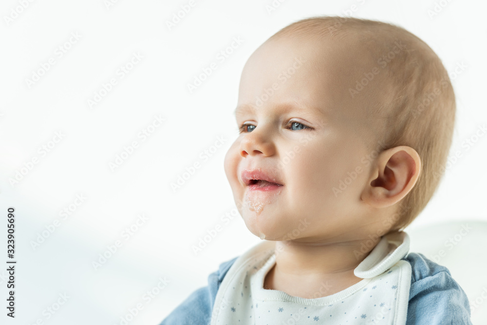 Cute baby boy with soiled mouth looking away on white background