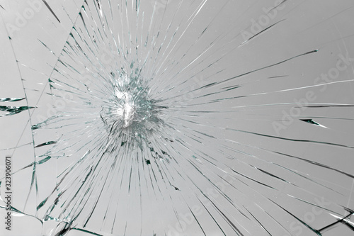 Cracks on broken glass from impact, white crack line fountain on window.