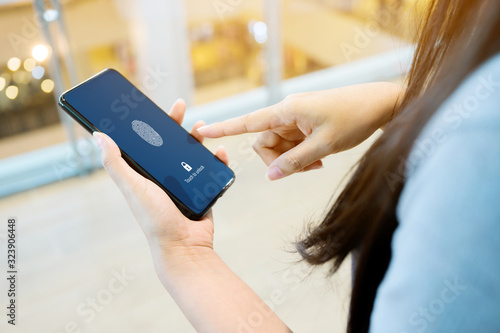 Hand women holding smartphone and scan fingerprint biometric identity for unlock her mobile phone photo