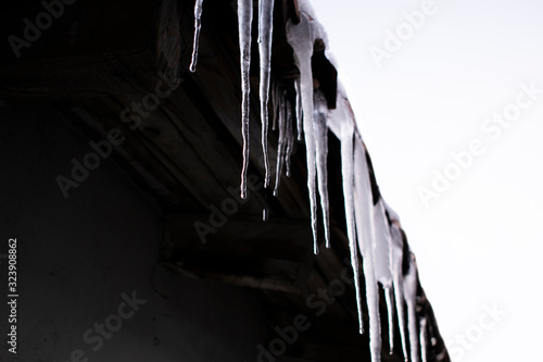 Iced water hanging from the roof. Dangerous sharp object. Seasonal scenery.